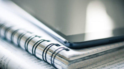 Tablet on top of a notebook.