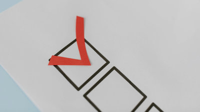 Red paper tick placed inside a black checkbox on a white sheet of paper.