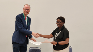 Two people shaking hands over agreeemnt.