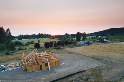 A partial built home stands onland which seems to have been cleared, unlike the surrounding feilds of grass.