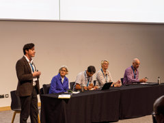 Panellists on stage at the annual conference in 2025 in Birmingham. There are four people seated and one standing
