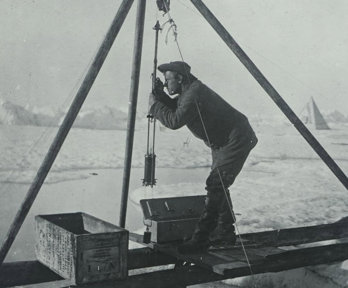 Old black and white photo of a person using scientific equipment in a polar environment.