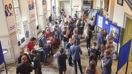 A large group of people seen from above while they are networking over tea and coffee in the main hall.