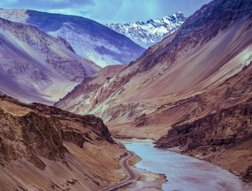 Mountain valley with a river and road running through the valley floor.
